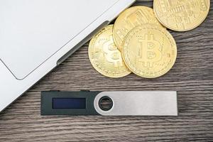 Hardware cryptocurrency wallet with golden Bitcoin BTC and computer. Safe storage for crypto. photo