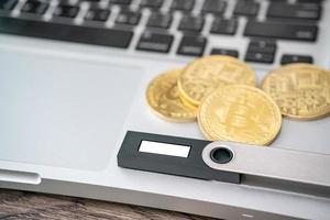 Hardware cryptocurrency wallet with golden Bitcoin BTC on computer. Safe storage for crypto. photo