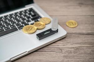 Hardware cryptocurrency wallet with golden Bitcoin BTC on computer. Safe storage for crypto. photo