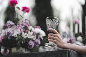 Glass of water in woman hand. Garden and flowers background. photo