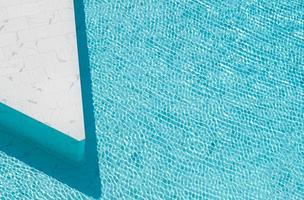 agua rasgada azul en la piscina hecha de baldosas de piedra de mármol blanco. foto