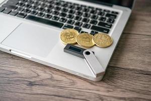 Hardware cryptocurrency wallet with golden Bitcoin BTC on computer. Safe storage for crypto. photo