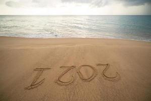 año de escritura 2021 sobre olas de arena y espuma en la playa. foto