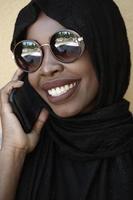 african  woman using smartphone wearing traditional islamic clothes photo