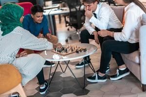 Multiethnic group of business people playing chess while having a break in relaxation area at modern startup office photo