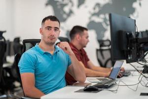 grupo de hombres de negocios casuales que trabajan en una computadora de escritorio en el moderno interior de la oficina de inicio de planta abierta. enfoque selectivo foto