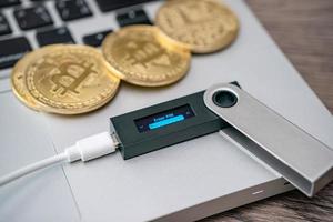 Hardware cryptocurrency wallet with golden Bitcoin BTC on computer. Safe storage for crypto. photo