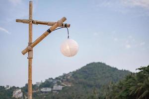 Bamboo pole and white lamp with blue sky and green mountain. photo