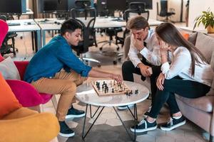 grupo multiétnico de empresarios jugando al ajedrez mientras descansan en el área de relajación en la moderna oficina de inicio foto