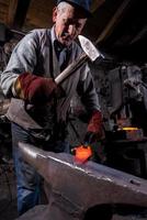 blacksmith manually forging the molten metal photo