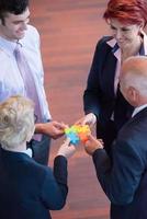 top view of business people group assembling jigsaw puzzle photo