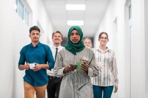 Multi-ethnic startup business team walking through the hallway of the building while coming back from a coffee break photo