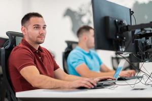 Group of Casual business man working on desktop computer in modern open plan startup office interior. Selective focus photo