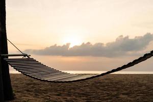 A wooden swing or cradle on the beach with beautiful cloud and sky. photo