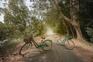 A bicycle on road with sunlight and green tree in park outdoor. photo
