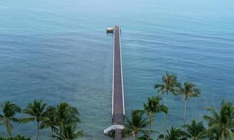 The bridge in to the sea. Tropical view with a concrete bridge to a pier on blue ocean. top view. photo