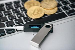 Hardware cryptocurrency wallet with golden Bitcoin BTC on computer. Safe storage for crypto. photo