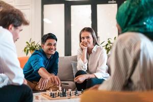Multiethnic group of business people playing chess while having a break in relaxation area at modern startup office. Selective focus photo
