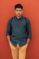 Startup business portrait of casual businessman with a blue shirt and backpack in front of red wall photo