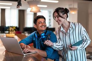 Multiethnic business people man with a female colleague working together on tablet and laptop computer in relaxation area of modern startup office photo