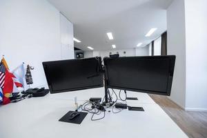 interior de oficina de inicio vacío con computadoras modernas y monitores de pantalla dual. enfoque selectivo foto