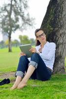 hermosa mujer joven con tableta en el parque foto