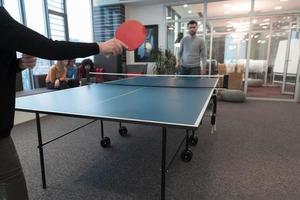 dos jóvenes emprendedores juegan al tenis de mesa en un espacio de oficina creativo moderno grupo de personas tienen reunión y lluvia de ideas en segundo plano foto