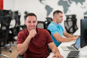 Group of Casual business man working on desktop computer in modern open plan startup office interior. Selective focus photo