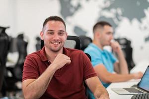 grupo de hombres de negocios casuales que trabajan en una computadora de escritorio en el moderno interior de la oficina de inicio de planta abierta. enfoque selectivo foto