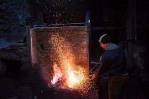 joven herrero tradicional trabajando con fuego abierto foto