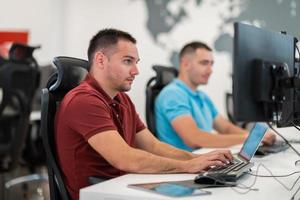 Group of Casual business man working on desktop computer in modern open plan startup office interior. Selective focus photo