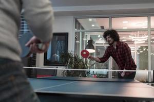 dos jóvenes emprendedores jugando tenis de ping pong en un espacio de oficina creativo moderno grupo de personas tienen reunión y lluvia de ideas en segundo plano foto