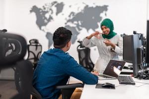 Multiethnic startup business team Arabian woman wearing a hijab on meeting in modern open plan office interior brainstorming, working on laptop and desktop computer. Selective focus photo