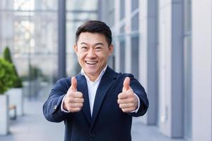 broker asian businessman in business suit happy looking at camera and showing thumbs up photo