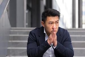 Asian office worker manager tired after work sitting on office stairs, dissatisfied photo