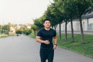 Male asian athlete running in the park in a backpack before work, running in the park photo