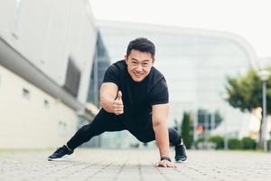 asian athlete performs sport pushing off the ground looks at the camera smiles and shows thumb up photo