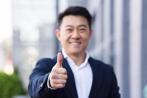 broker asian businessman in business suit happy looking at camera and showing thumbs up photo