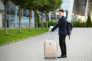 Happy Asian tourist with a big suitcase near the airport, at a business meeting arrives looking photo