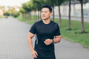 Male asian athlete running in the park in a backpack before work, running in the park photo