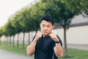 Male asian athlete demonstrates boxing rack during morning jogging and fitness photo