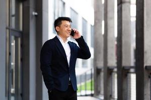 Asian businessman talking on the phone cheerful smiling reports good news photo