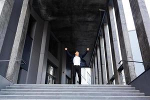 Happy and cheerful asian businessman holding hands up rejoicing in victory and success photo