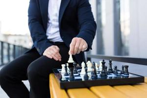 Close-up photo of businessman's hands making a move on a chessboard, male businessman playing chess