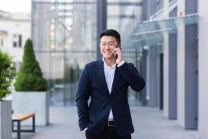Successful asian businessman businessman talking on cell phone while walking photo