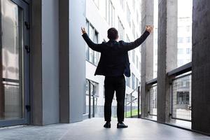 Successful businessman raises his hands up a sign of victory and success near photo