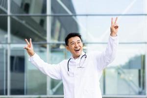 portrait of a cheerful Asian doctor man dancing happy with the results of the work done photo