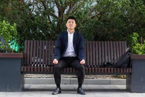 Asian businessman performing breathing exercises trying to calm stress photo