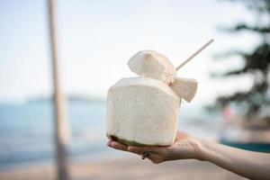 Fresh coconut cocktail in hand over ocean background. photo