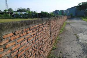 una pared larga con ladrillos rojos al borde de un campo de arroz foto